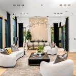 Modern living room with stylish furniture, large windows, and contemporary decor, featuring a dining area and bar counter.